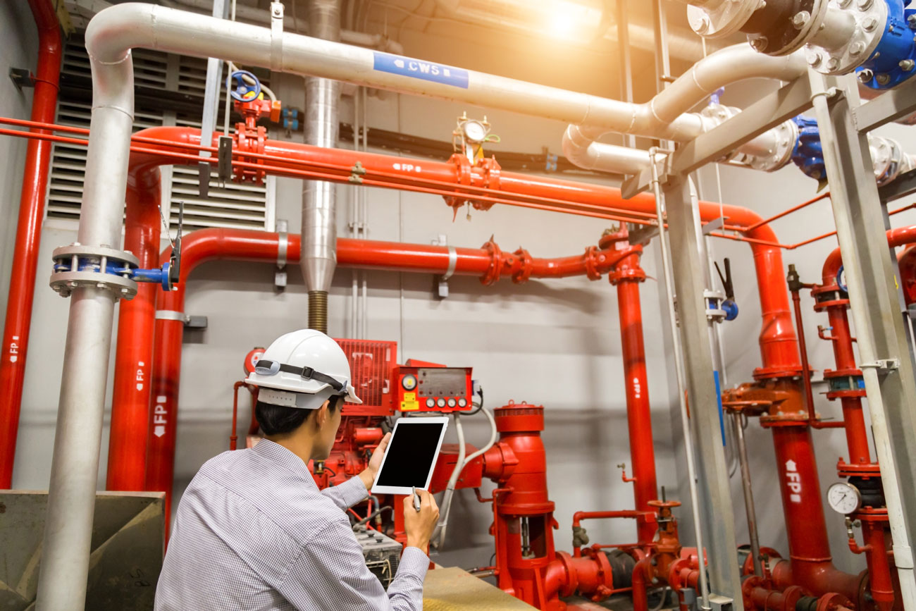 A safety auditor inspects site safety equipment using a tablet with fire-safety checklist software. (PlanRadar)